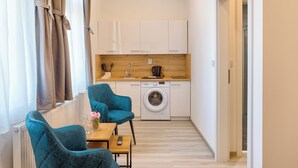 A narrow hallway with a kitchen area, a washing machine, and a table with chairs.