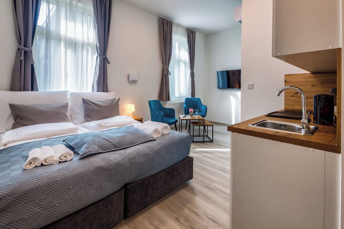 A hotel room with a bed, a small table with a chair, a sink, and a TV mounted on the wall.