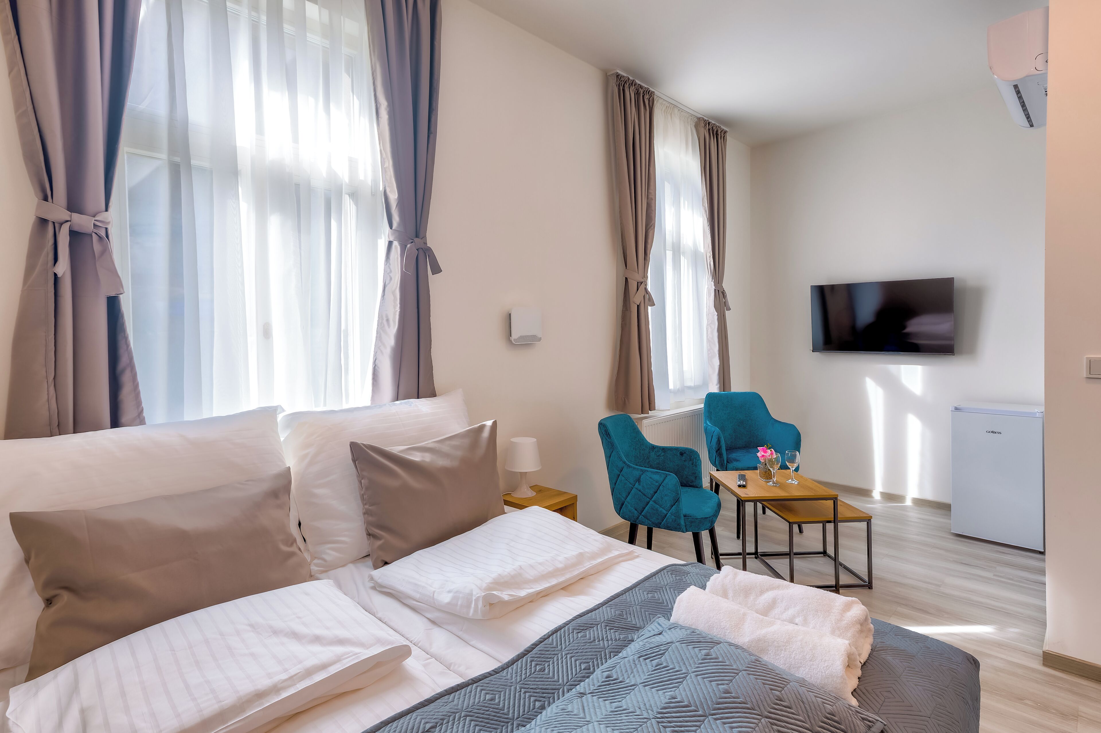 A hotel room with a bed, a desk with a chair, a television, and a mini-fridge.