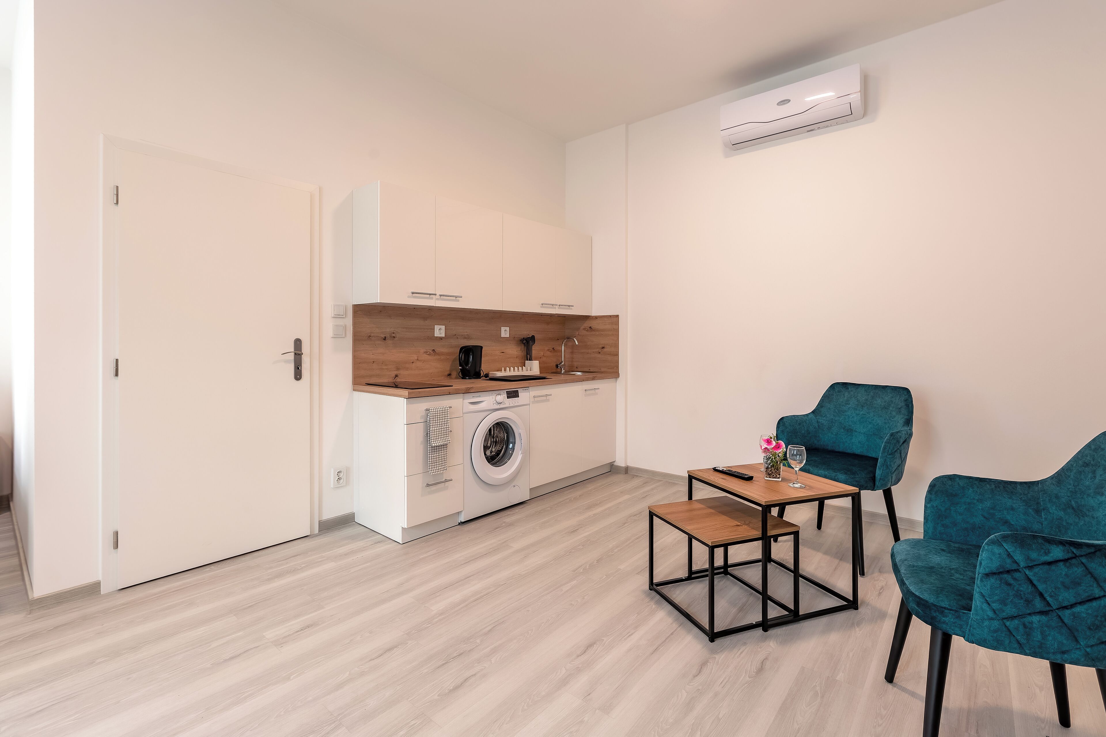 Eine moderne Küche mit Waschmaschine, einer Essecke mit Tisch und Stühlen sowie einer großen Klimaanlage an der Wand.