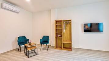 Un soggiorno moderno con una libreria in legno, due poltrone color petrolio, un tavolino in legno e una TV a parete.