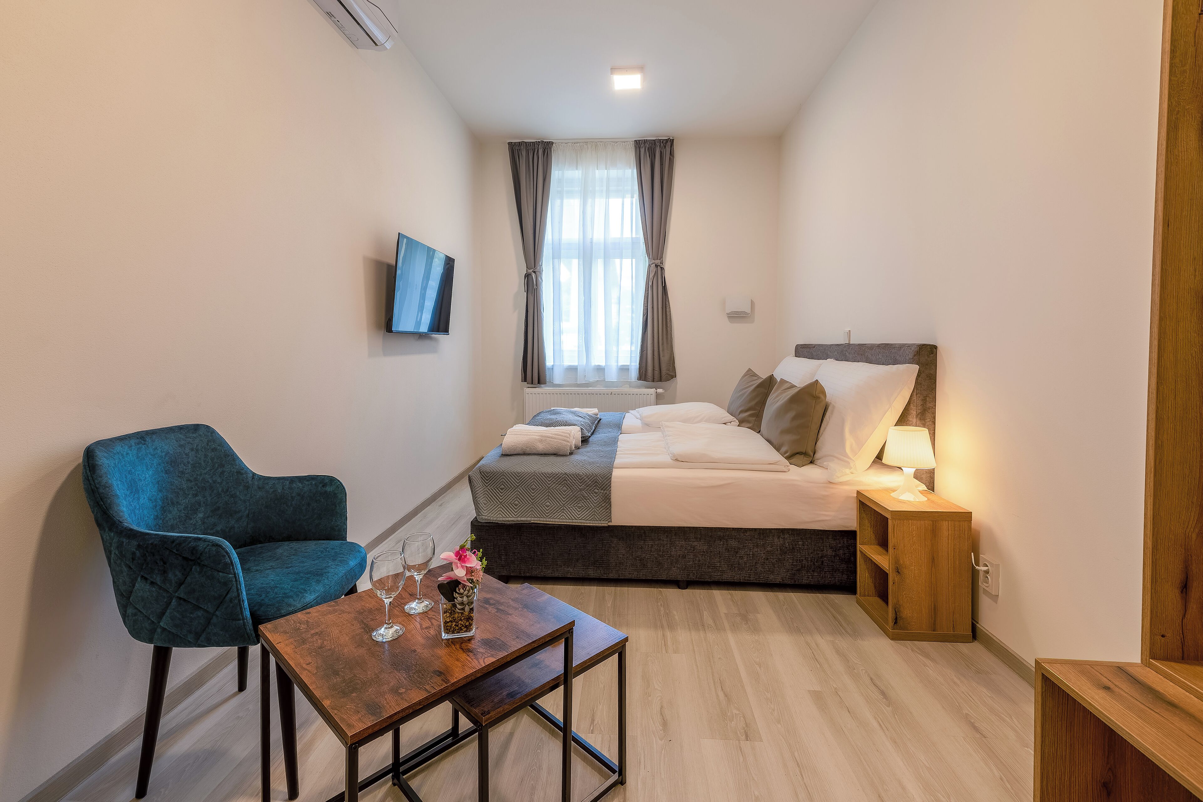 Un dormitorio pequeño con cama, mesita de noche, lámpara y una silla azul.