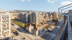 A cityscape with a prominent ancient archway, modern buildings, and a clear sky. - Aether by halu (Thessaloniki)