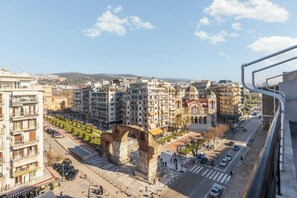 A cityscape with a prominent ancient archway, modern buildings, and a clear sky. - Aether by halu (Thessaloniki)