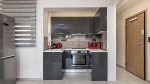 A modern kitchen with stainless steel appliances, a built-in oven, and a microwave. - Aether by halu (Thessaloniki)