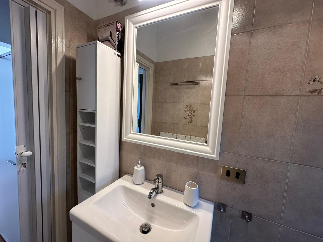 A bathroom with a white sink, a mirror, and a towel rack.