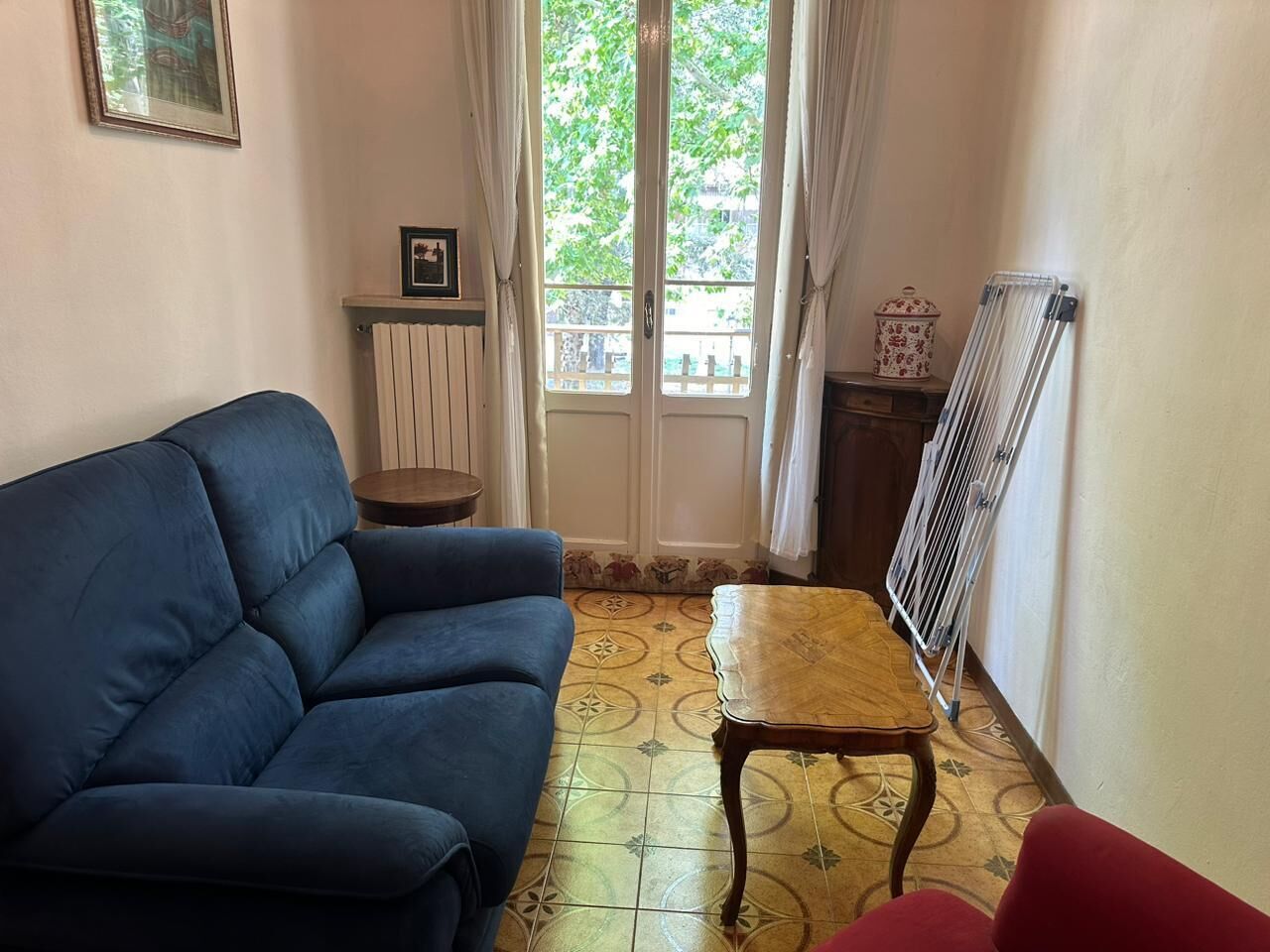 A living room with a blue sofa, a wooden table, and a radiator.