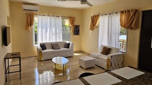 A spacious living room with a sofa, a coffee table, and a TV. - Luxury 8 King BR  w/ Private Pool, & Event Space (Sosua)