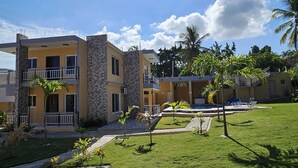 A multi-story hotel with balconies, a swimming pool, and a well-maintained lawn. - Luxury 8 King BR  w/ Private Pool, & Event Space (Sosua)