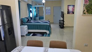 A compact hotel room with a bed, a desk, a chair, and a refrigerator. - Luxury 8 King BR  w/ Private Pool, & Event Space (Sosua)