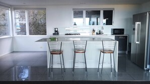 A modern kitchen with a central island, stainless steel appliances, and large windows. - Esplanade Azure Horizon (Wellington)