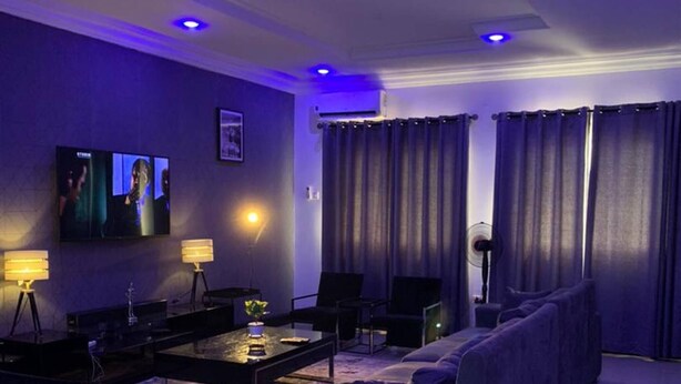 A modern living room with a sofa, chairs, a coffee table, and a TV. - 3 Bed Apartment at a Central Location (Ibadan)