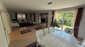 A spacious living area with a dining table, sofa, TV, and large windows. - House in Hannover/Laatzen! contactless check-in (Laatzen)
