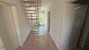 A hallway with a staircase, white walls, and a tiled floor. - House in Hannover/Laatzen! contactless check-in (Laatzen)