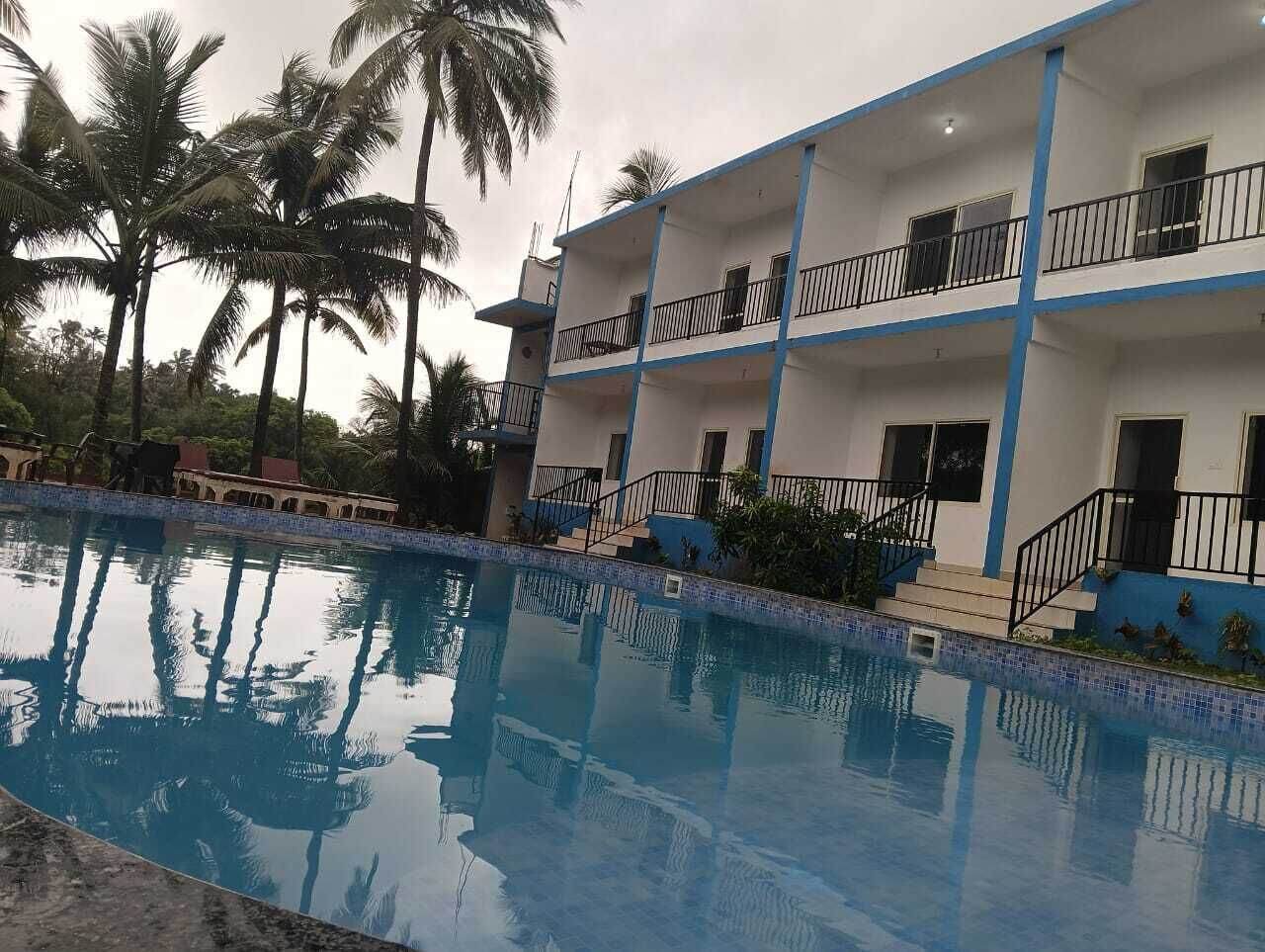 A hotel with a swimming pool, balconies, and palm trees.
