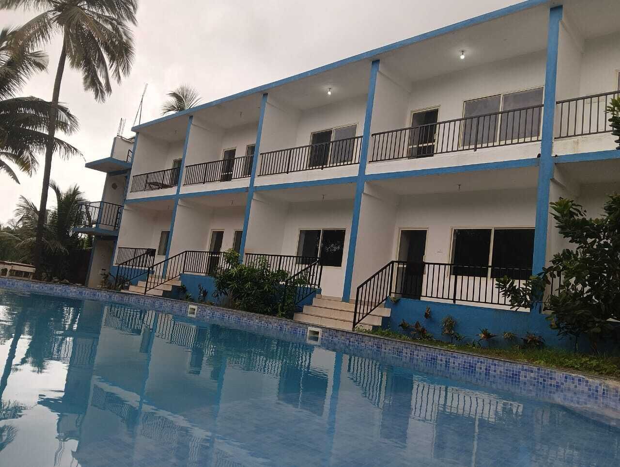 A multi-story hotel with balconies, a swimming pool, and palm trees.
