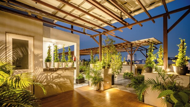A rooftop terrace with wooden flooring, potted plants, and a view of the city skyline. - Royal Studio Golf Course Road (Sohna)