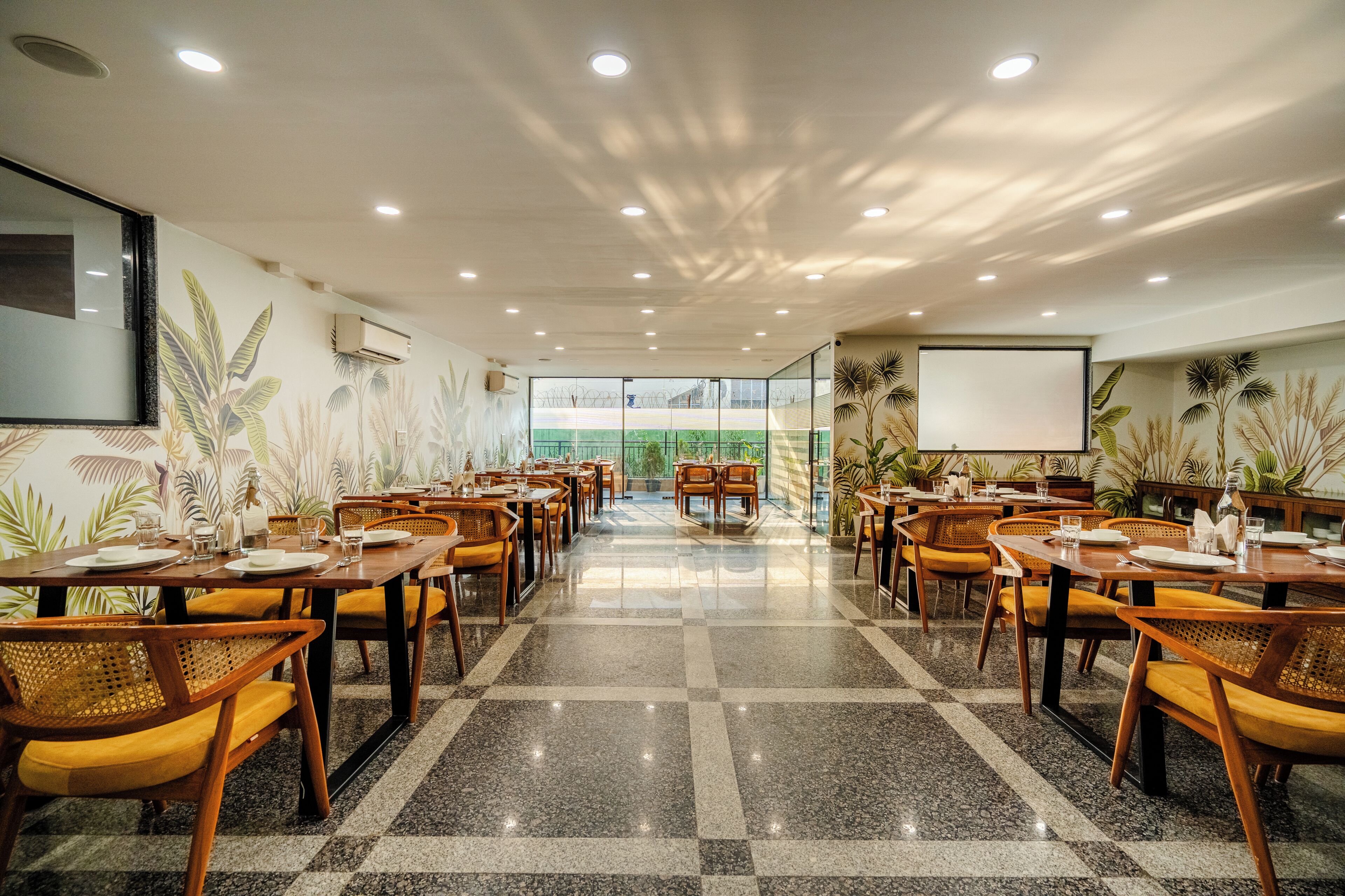 Un'ampia sala da pranzo con diversi tavoli e sedie, un pavimento lucido e un'ampia finestra che offre vista sull'esterno.