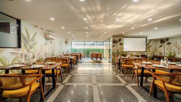 Un'ampia sala da pranzo con diversi tavoli e sedie, un pavimento lucido e un'ampia finestra che offre vista sull'esterno.