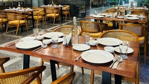 A modern dining area with wooden tables and chairs, glass partitions, and recessed ceiling lighting. - Royal Studio Golf Course Road (Sohna)