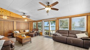 Ein geräumiges Wohnzimmer mit einem braunen Ledersofa, einem Holztisch und einem Deckenventilator.