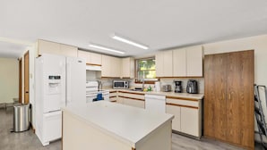 Eine moderne Küche mit weißen Geräten, Holzschränken und einer zentralen Kochinsel.
