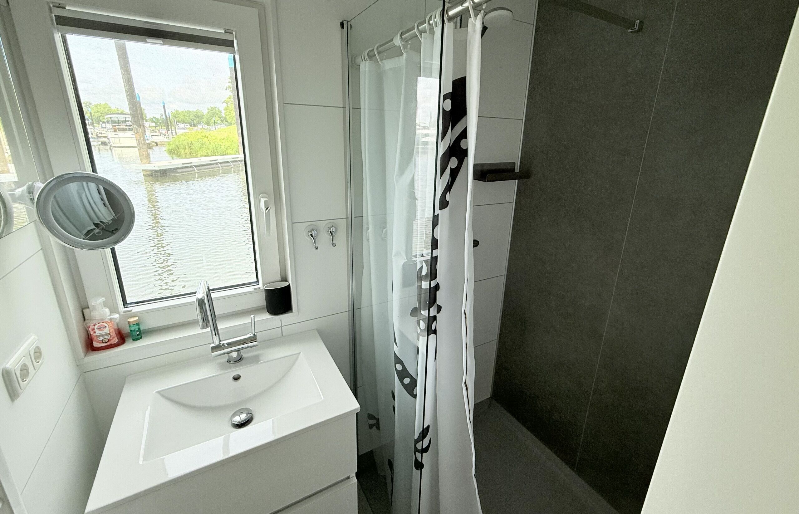 A bathroom with a window, a sink, a mirror, and a shower curtain.