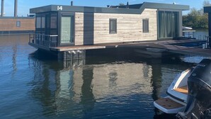 A modern houseboat with a flat roof, large windows, and a dock. - Maasterp - Watervillage 14 (Ohé en Laak)