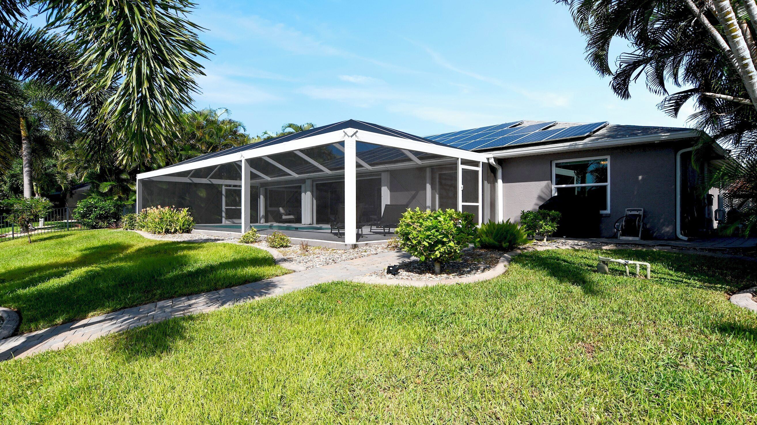 A house with a covered patio, a swimming pool, and a well-maintained lawn.