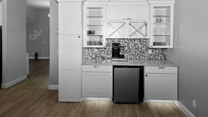 A compact kitchen with white cabinetry, a black refrigerator, and a tiled backsplash. - Mei Jing Waterfront Pool and Tiki Hut-must see (Cape Coral)
