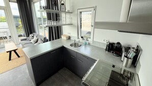 Una cocina moderna con una isla integrada, electrodomésticos de acero inoxidable y un amplio ventanal con vistas a un balcón.