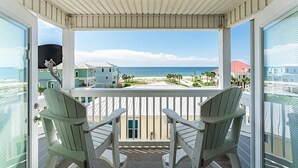 A balcony with two Adirondack chairs overlooking a beach and ocean. - Huge beach-side townhouse located steps to the sand in Mexico Beach! (Mexico Beach)
