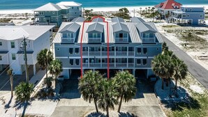 A beachfront hotel with multiple balconies, a parking area, and palm trees. - Huge beach-side townhouse located steps to the sand in Mexico Beach! (Mexico Beach)