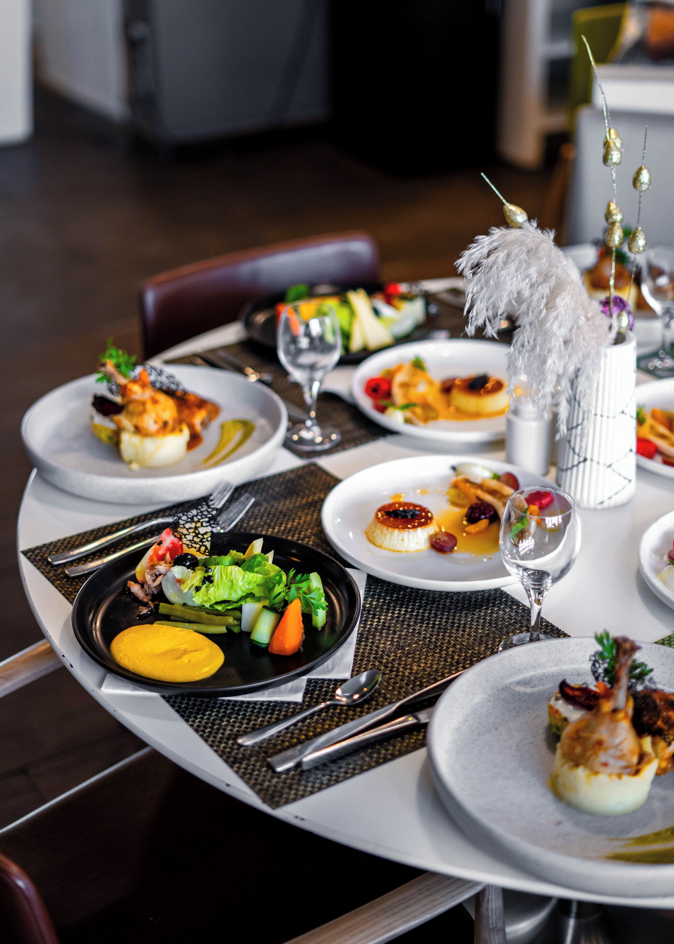 A dining table set with various dishes, including a salad, a dessert, and a glass of wine.