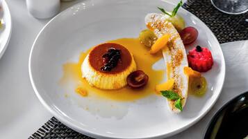 A dining table with a white plate of dessert, a glass of wine, and salt and pepper shakers.