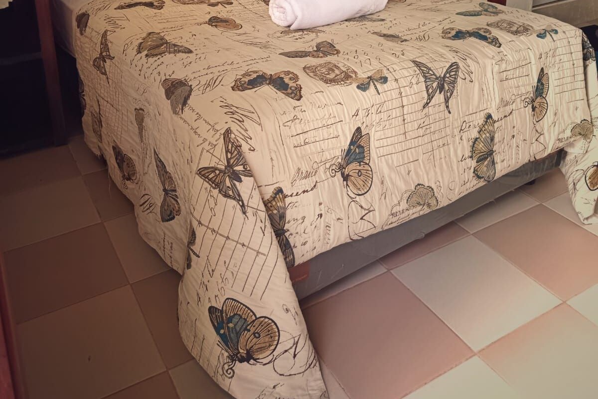 A bedroom with a wooden bed, a white pillow, and a patterned bedspread.