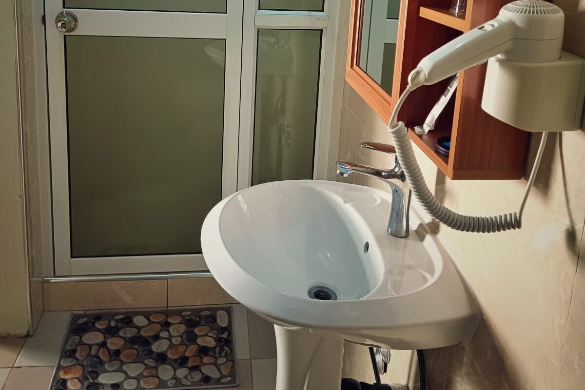 A bathroom with a white sink, a mirror, and a hairdryer.