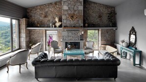 A spacious living room with a stone fireplace, leather sofa, and classic armchairs. - Mila House (Ayvacik)
