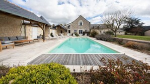 A stone house with a swimming pool, outdoor seating, and a wooden deck.