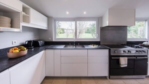 A modern kitchen with white cabinets, a black countertop, a gas stove, and a large window providing natural light.