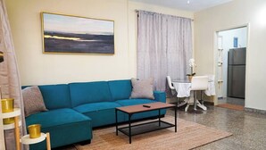 A living room with a teal sofa, a coffee table, and a painting on the wall.