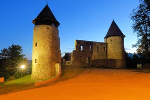 A historic stone castle with two prominent towers and a well-lit entrance. - Riverside House With Pool and Hot Tub (Karlovac)