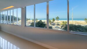 Ein Hotelkorridor mit großen Fenstern, die Blick auf einen Strand und Palmen bieten.