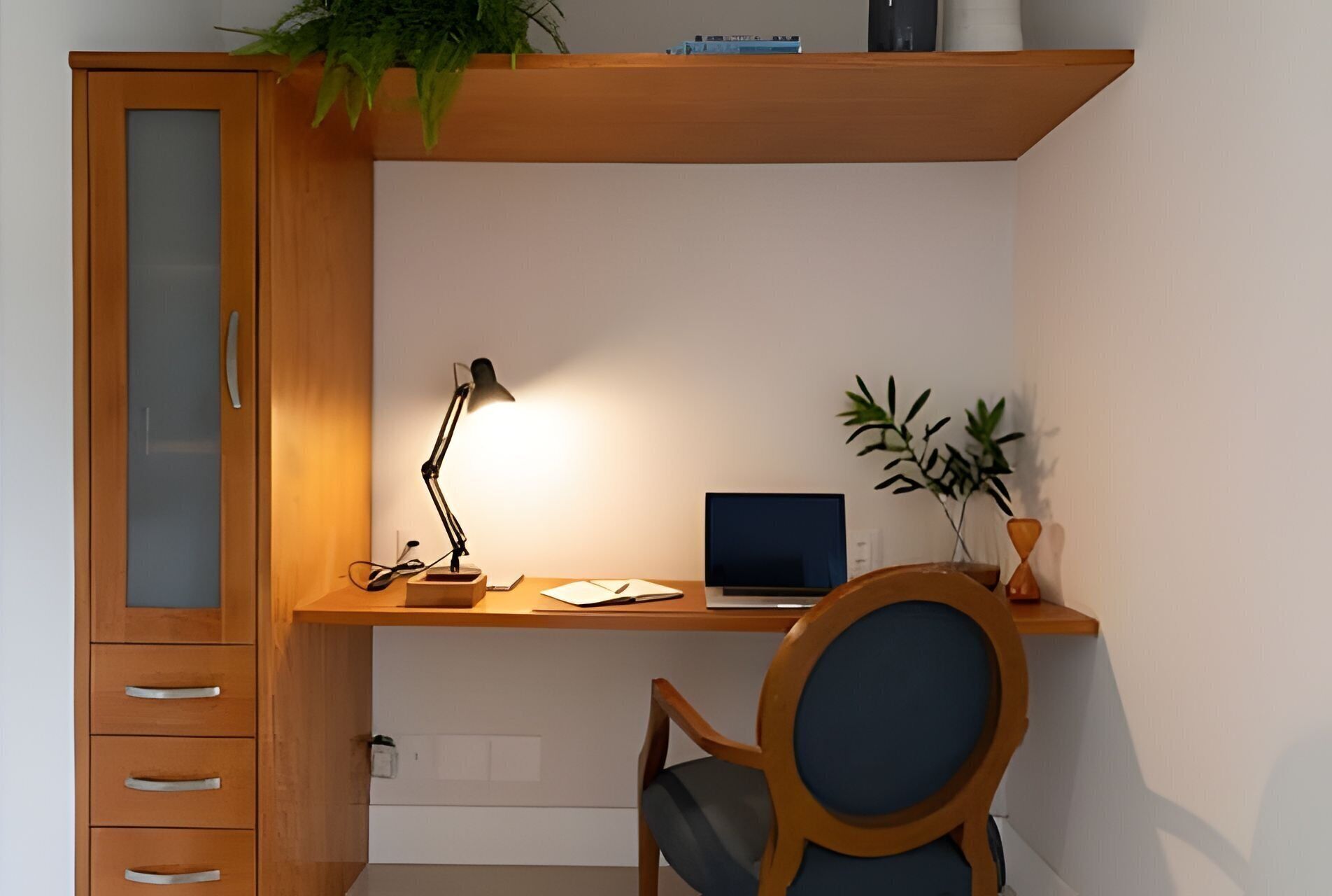 Un espace de travail compact comprenant un bureau, une chaise, un ordinateur portable et une lampe.