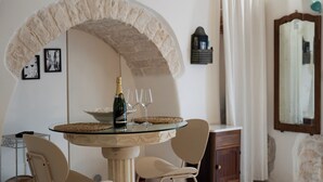Un coin repas avec une table ronde en verre, une bouteille de champagne et deux verres à vin.