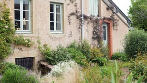 Ein rustikales Gebäude mit Backsteinportal, einem kleinen Fenster mit Holzklappe und einer Steinwand.