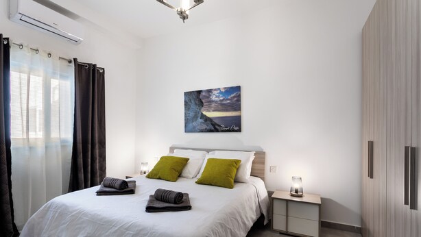 Een moderne slaapkamer met een bed, nachtkastje en wanddecoratie.