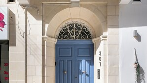 Een blauwe deur met het cijfer 301 erboven, een metalen poort en een stenen muur.