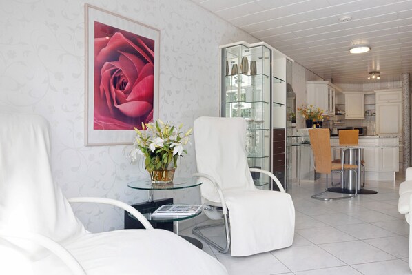 A modern interior with white furniture, a glass table, and a framed rose painting.