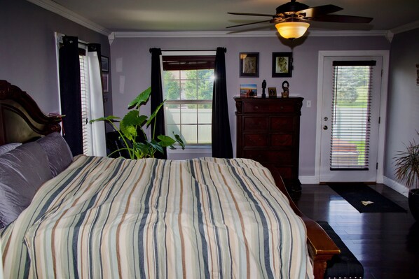 Une chambre à coucher avec un grand lit, un ventilateur de plafond, une commode et une fenêtre avec des rideaux.